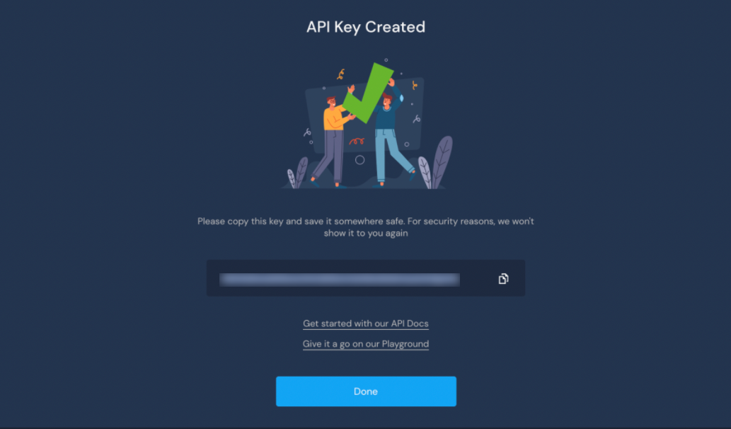 The image shows the success screen after you create an API Key. At the top, it says "API Key Created". There is a drawing of two people holding up a green checkmark. The API Key in this screen shot is blurred out. Beneath the key there is a blue button labeled "Done."